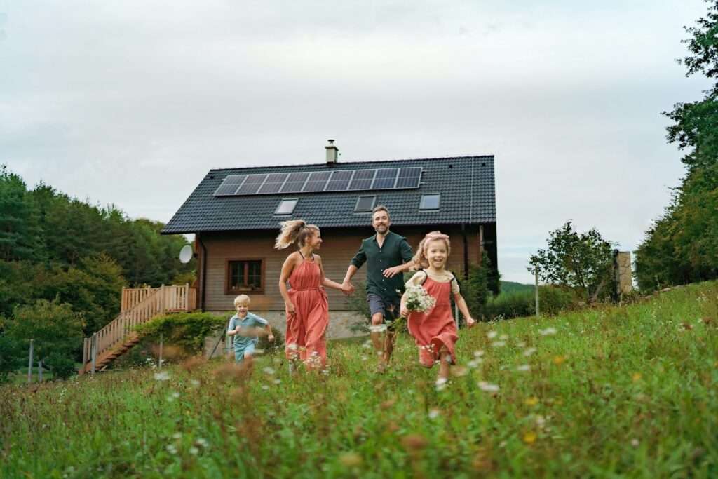 Happy family running near their house with solar panels. Alternative energy, saving resources and